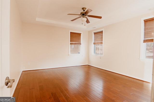 unfurnished room with ceiling fan, wood-type flooring, and a tray ceiling