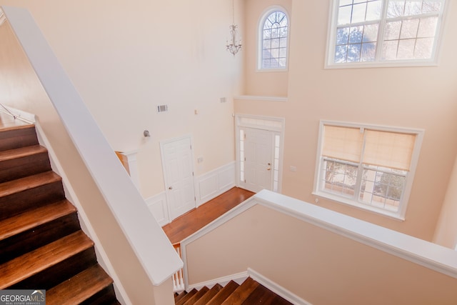 stairway with an inviting chandelier and a towering ceiling