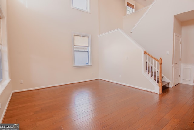 unfurnished living room with a high ceiling, a healthy amount of sunlight, and hardwood / wood-style floors