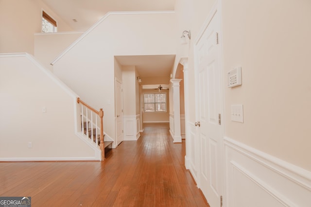 hallway with hardwood / wood-style floors, a high ceiling, a wealth of natural light, and decorative columns