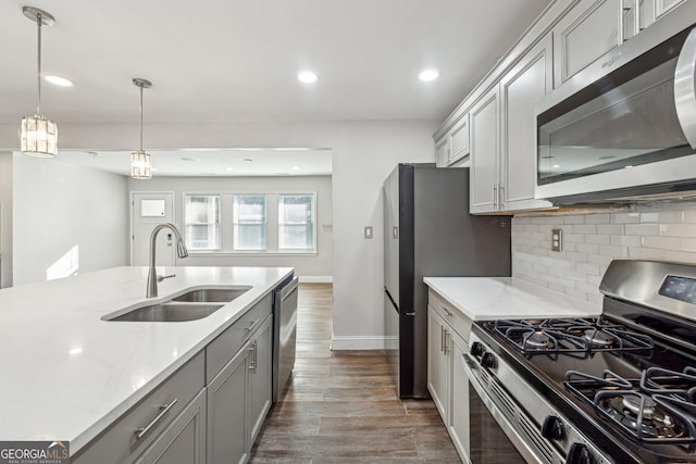 kitchen with gray cabinets, light stone counters, sink, and stainless steel appliances