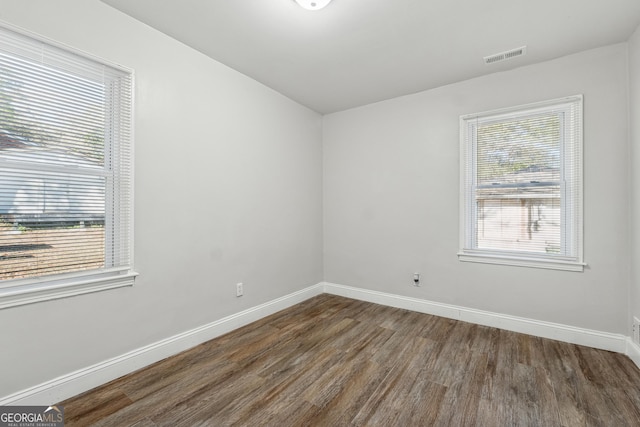 unfurnished room featuring plenty of natural light and dark hardwood / wood-style flooring