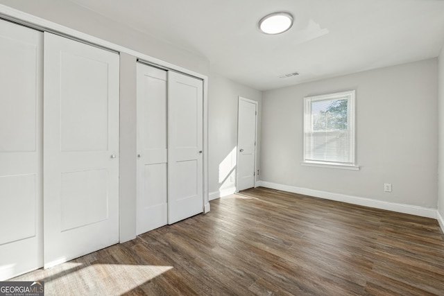 unfurnished bedroom featuring dark hardwood / wood-style floors and two closets