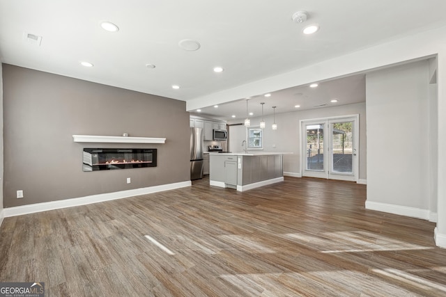 unfurnished living room featuring hardwood / wood-style floors and sink