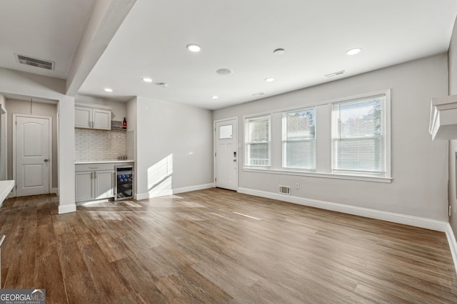 unfurnished living room featuring hardwood / wood-style floors and beverage cooler