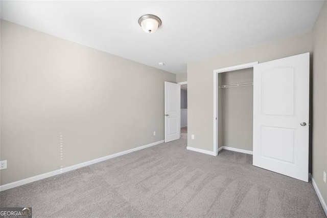 unfurnished bedroom with a closet and light colored carpet