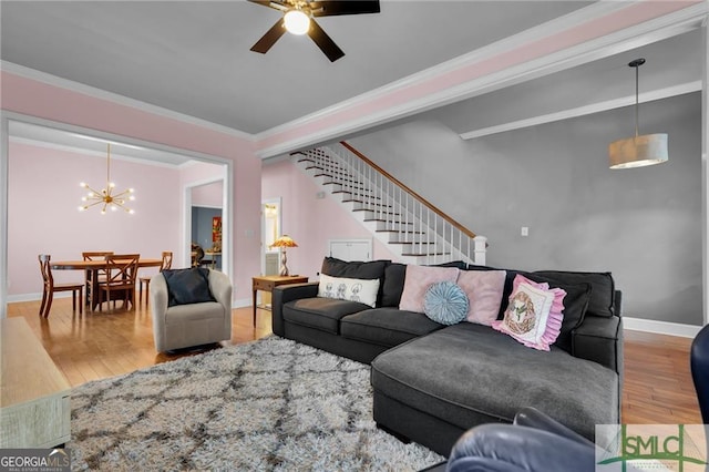 living room with hardwood / wood-style flooring, ceiling fan with notable chandelier, and crown molding