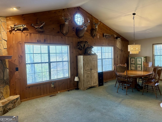 carpeted dining room with wood walls and vaulted ceiling