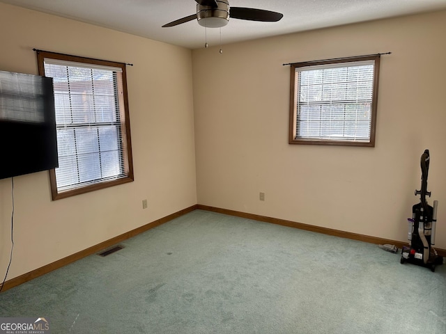 spare room featuring a wealth of natural light, ceiling fan, and light carpet