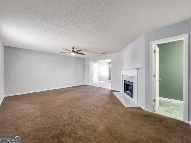 unfurnished living room with a high end fireplace, a textured ceiling, ceiling fan, and carpet flooring