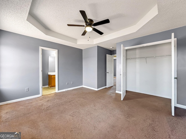 unfurnished bedroom with a raised ceiling, carpet, a textured ceiling, and a closet