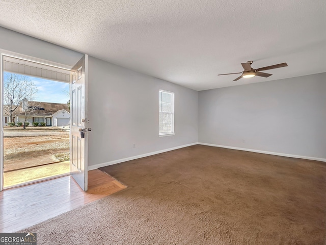 unfurnished room with ceiling fan, a textured ceiling, and dark carpet