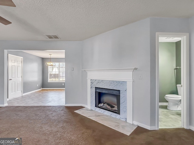 unfurnished living room featuring ceiling fan with notable chandelier, a premium fireplace, a textured ceiling, and carpet