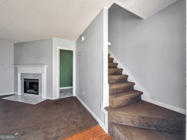 staircase with a fireplace and a textured ceiling