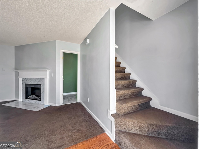 staircase featuring carpet flooring, a fireplace, and a textured ceiling