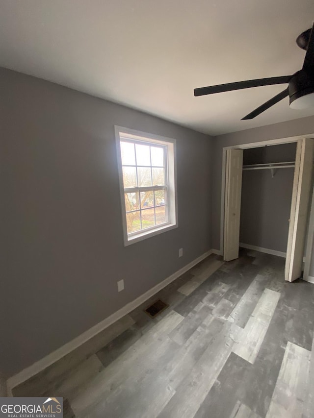 unfurnished bedroom with ceiling fan, light wood-type flooring, and a closet