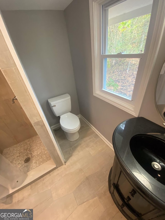 bathroom with tiled shower, tile patterned flooring, and toilet