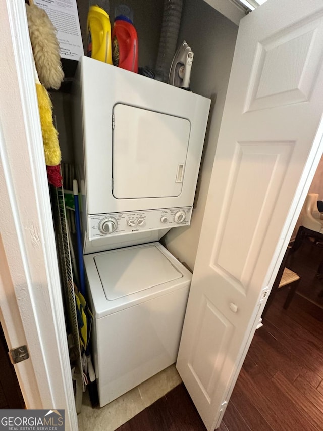 clothes washing area with stacked washer / dryer and dark hardwood / wood-style flooring