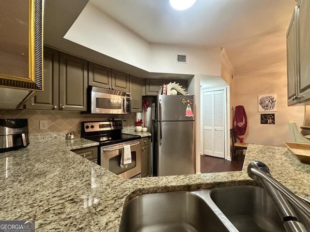 kitchen featuring sink, light stone countertops, stainless steel appliances, and tasteful backsplash