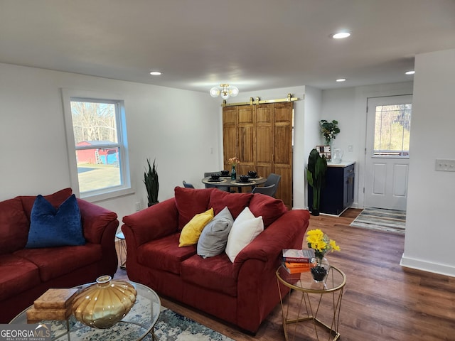 living room with a barn door, dark hardwood / wood-style flooring, and plenty of natural light