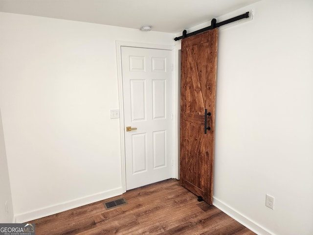 unfurnished room with hardwood / wood-style floors and a barn door