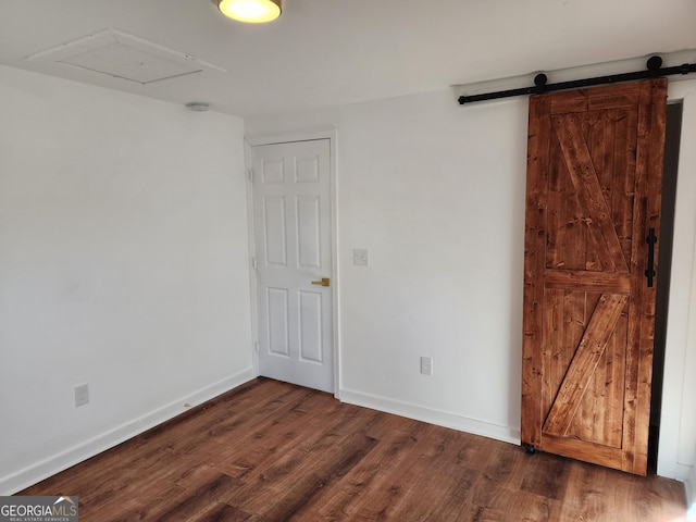 unfurnished room featuring a barn door and dark hardwood / wood-style floors