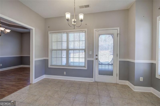 doorway to outside with light tile patterned floors and a notable chandelier