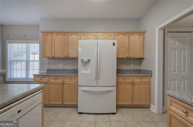 kitchen featuring decorative backsplash, light brown cabinetry, white appliances, and light tile patterned floors