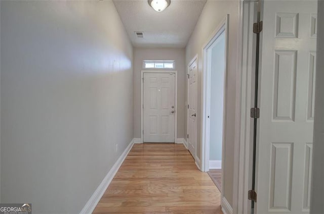 doorway featuring light hardwood / wood-style floors and a textured ceiling