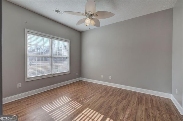 spare room with ceiling fan, a textured ceiling, and hardwood / wood-style flooring