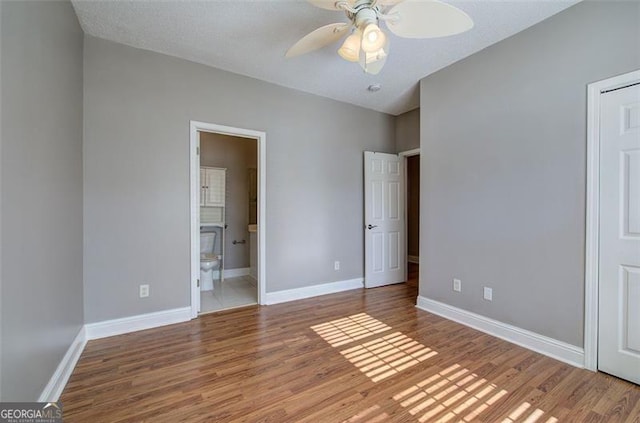 unfurnished bedroom featuring ensuite bathroom, ceiling fan, and wood-type flooring