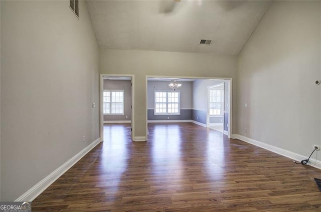 empty room featuring dark hardwood / wood-style flooring, vaulted ceiling, and a notable chandelier