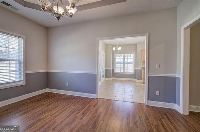 empty room featuring hardwood / wood-style flooring, plenty of natural light, and an inviting chandelier