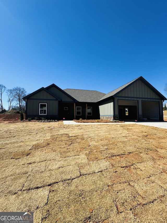 view of front of home with a garage, board and batten siding, and roof with shingles