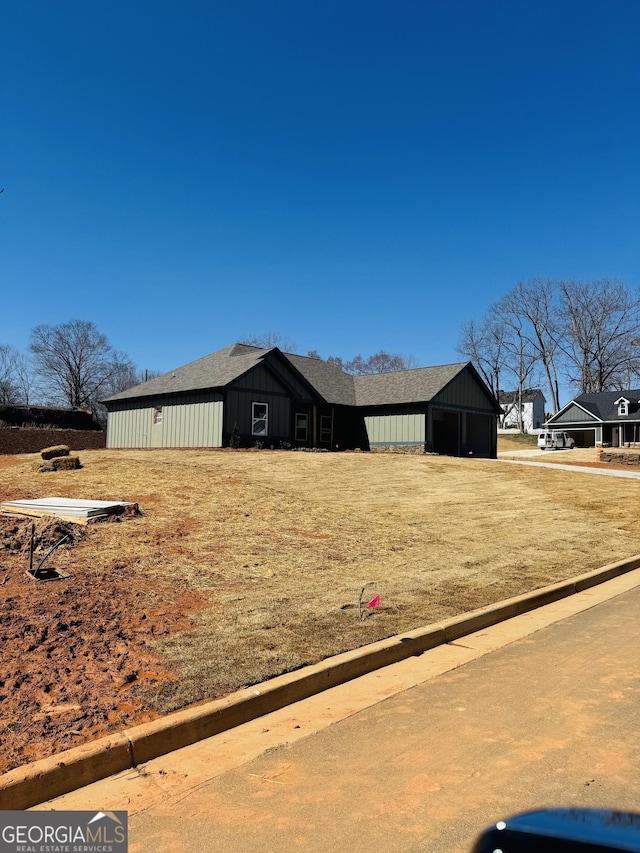 view of side of home with driveway, a detached garage, and board and batten siding