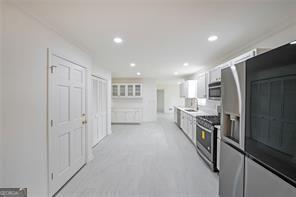 kitchen with stainless steel electric stove, fridge with ice dispenser, and white cabinets