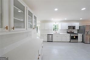 kitchen featuring decorative backsplash, appliances with stainless steel finishes, white cabinetry, and sink