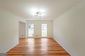 empty room with crown molding, hardwood / wood-style floors, and an inviting chandelier