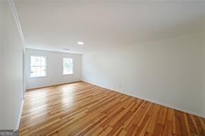 spare room featuring crown molding and light hardwood / wood-style floors