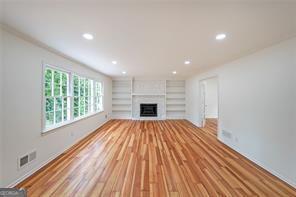 unfurnished living room with a large fireplace, light hardwood / wood-style floors, and built in features