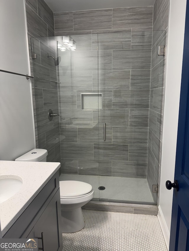 bathroom featuring toilet, vanity, tile patterned floors, and a shower with shower door