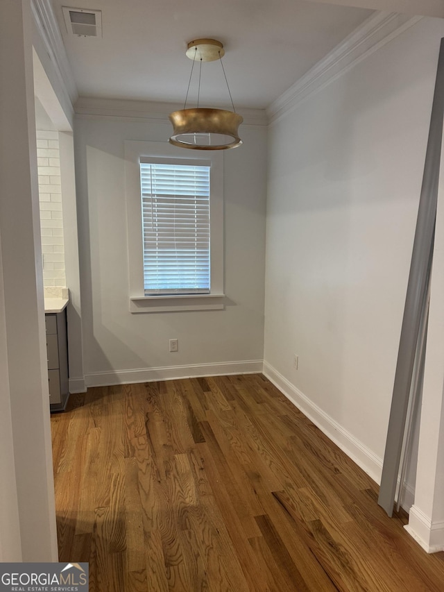 unfurnished dining area featuring dark hardwood / wood-style flooring and ornamental molding