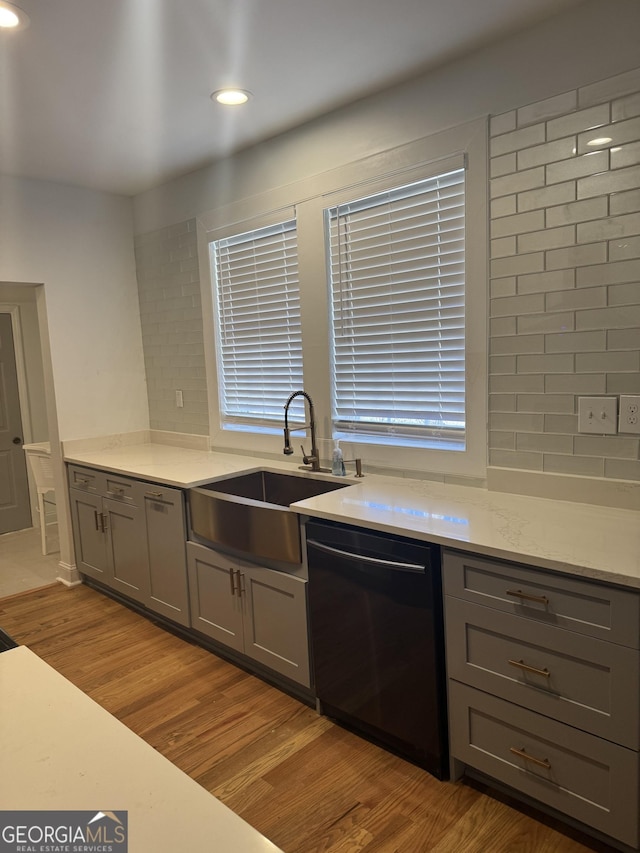 kitchen with gray cabinetry, backsplash, sink, and black dishwasher