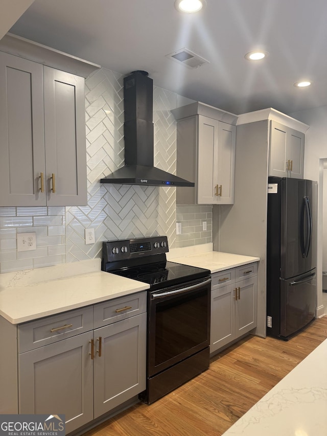 kitchen with backsplash, wall chimney exhaust hood, gray cabinets, stainless steel fridge, and black range with electric cooktop