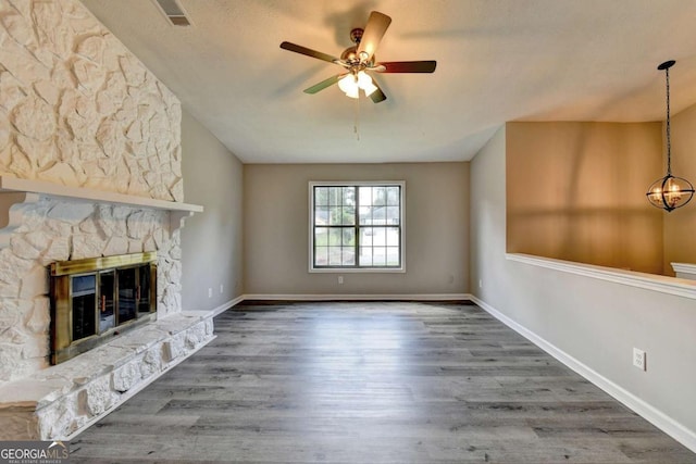 unfurnished living room with hardwood / wood-style flooring, ceiling fan, and a fireplace