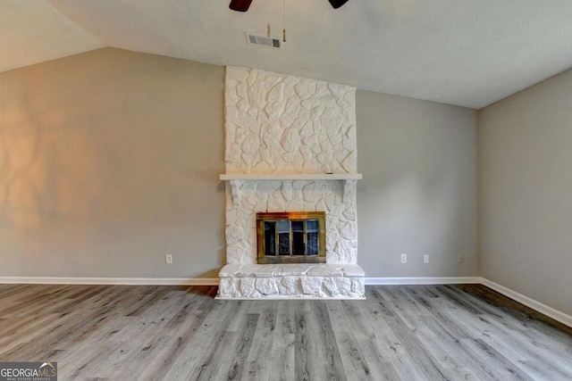 unfurnished living room featuring hardwood / wood-style floors, ceiling fan, lofted ceiling, and a fireplace