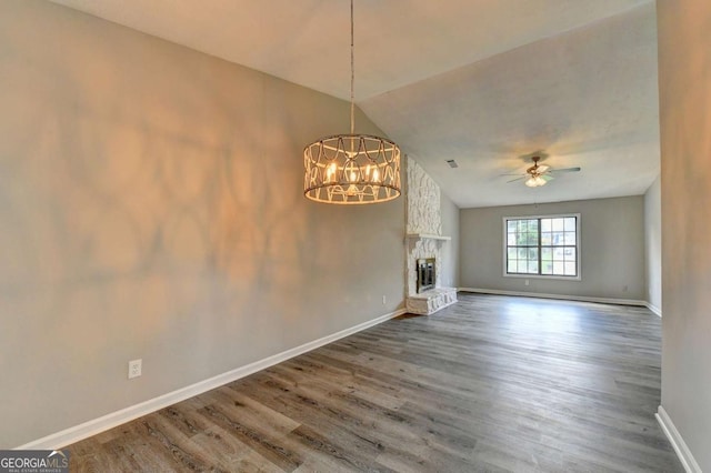 unfurnished living room featuring ceiling fan with notable chandelier, a stone fireplace, lofted ceiling, and wood-type flooring