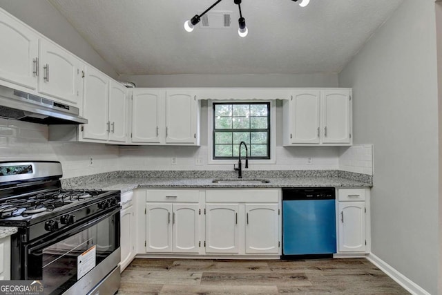 kitchen with white cabinets, stainless steel appliances, light stone counters, and sink