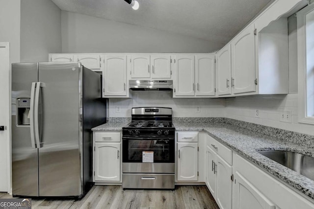 kitchen featuring decorative backsplash, light stone counters, stainless steel appliances, white cabinetry, and lofted ceiling