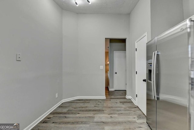 corridor featuring light wood-type flooring and a textured ceiling